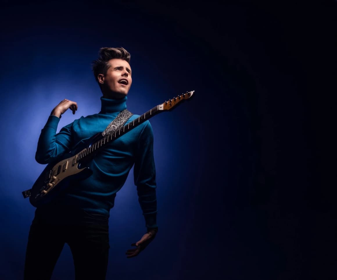 Roman Roses, en pull bleu, une guitare à la main
